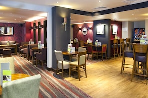 A hotel lobby with multiple seating areas, including a bar and a dining area with tables and chairs. - Premier Inn London Blackfriars (London)