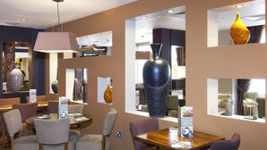 A restaurant with multiple dining tables and chairs, a large vase, and a mirror on the wall. - Premier Inn London Blackfriars (London)