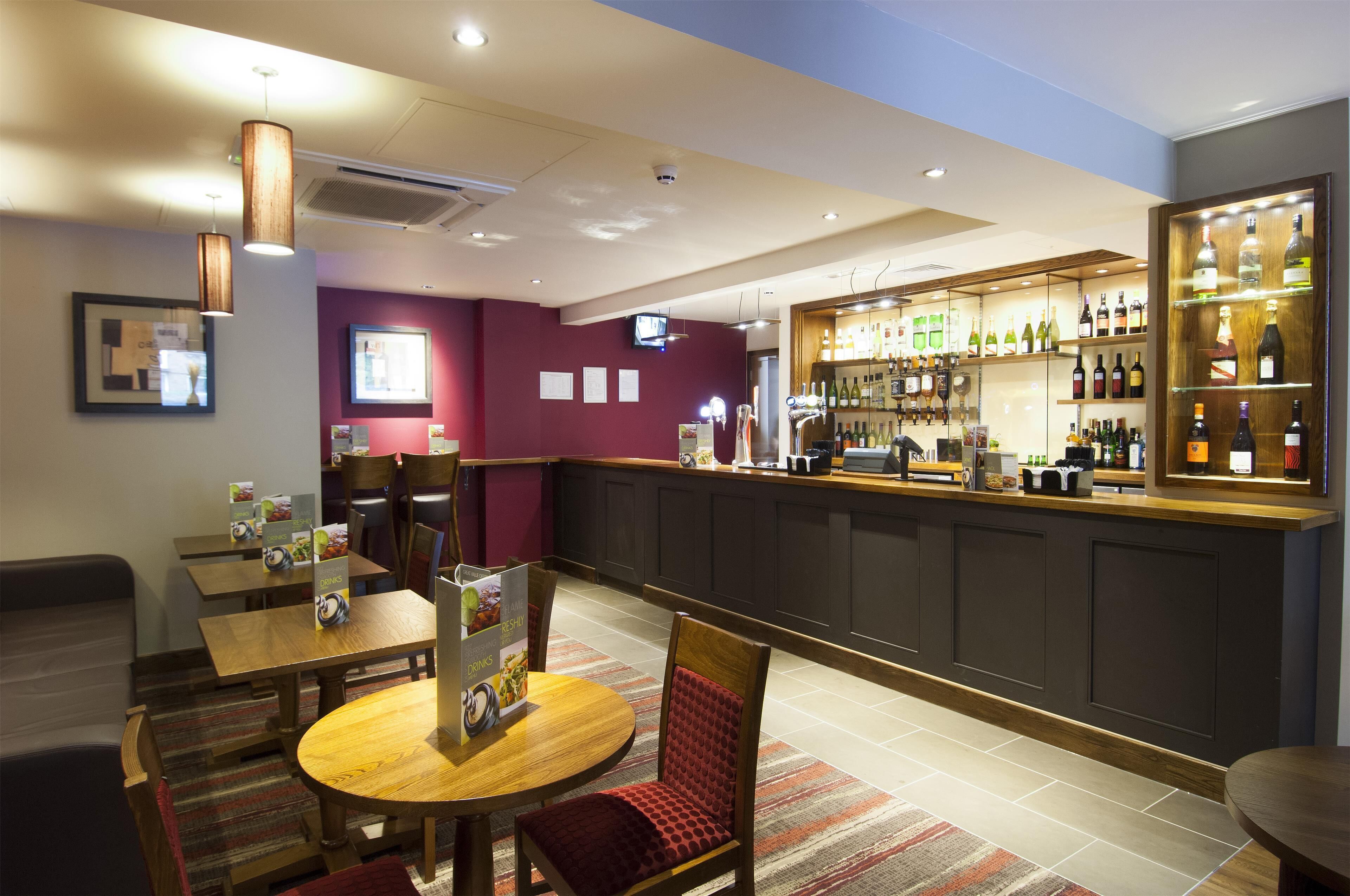 A bar area with a counter, seating, and a display of bottles.