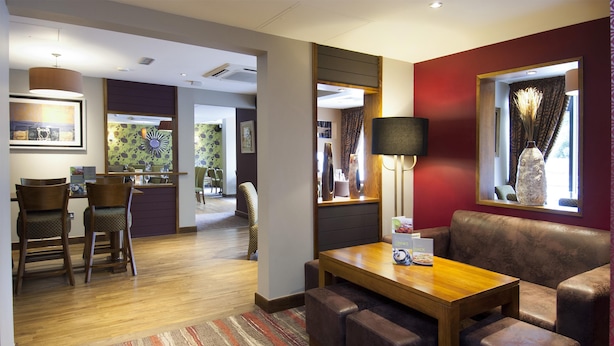 Een hotelkamer met een houten eettafel, een leren bank en een grote spiegel.