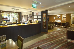 Eine Bar mit einer Theke, Sitzplätzen und einem gemusterten Teppich.