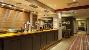 Een hotel receptie met een balie, koffieautomaten en een eetgedeelte op de achtergrond.