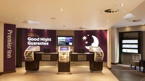 A check-in area at a Premier Inn with self-service kiosks and a digital display. - Premier Inn London Croydon Town Centre (Croydon)