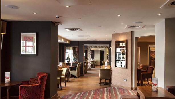 A hotel lobby with a patterned carpet, seating areas, and a bar. - Premier Inn London Croydon Town Centre (Croydon)