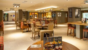 A restaurant with multiple dining areas, a bar, and a counter with stools. - Premier Inn London Hendon - The Hyde (London)