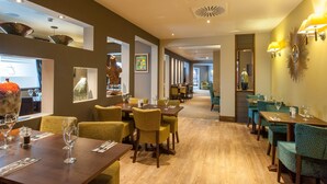 Un restaurante con mesas y sillas de madera, una barra larga y vista al comedor.