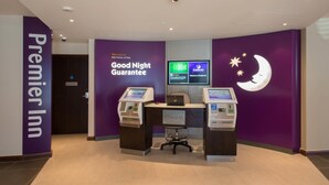 A check-in area with a computer monitor, a self-service kiosk, and a sign reading 'Good Night Guarantee.' - Premier Inn London Edmonton (London)