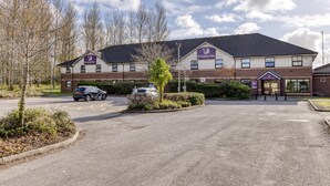 Un hotel Premier Inn con un estacionamiento, un coche y un cielo despejado.