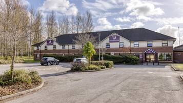 A Premier Inn hotel with a parking lot, a car, and a clear sky.