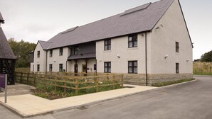 A two-story building with a flat roof, multiple windows, and a wooden fence in front. - Premier Inn Llandudno - Glan-Conwy (Colwyn Bay)