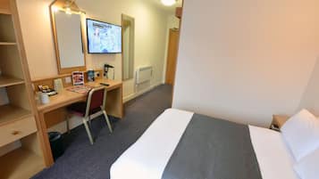 Une chambre d’hôtel équipée d’un lit, d’un bureau, d’une chaise, d’un miroir, d’une télévision et d’un radiateur.