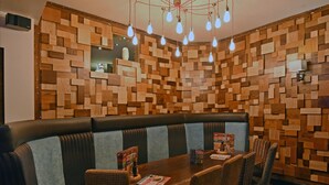 Un restaurant dont le décor est caractérisé par un mur en bois, des tables en bois et des sièges rembourrés.