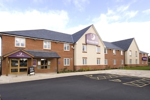 A Premier Inn hotel with a brick facade, multiple windows, and a parking lot with disabled parking spaces. - Premier Inn Rhuddlan (Rhuddlan)