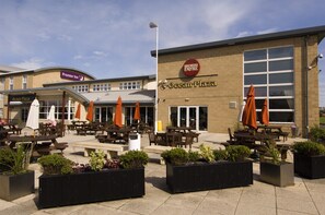 An outdoor seating area with tables and chairs, surrounded by planters and umbrellas. - Premier Inn Southport Central (Southport)