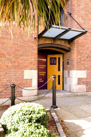 A brick building with a wooden door labeled 'touchbase meeting rooms,' a business lounge, and hot desks. - Premier Inn Liverpool City - Albert Dock (Liverpool)