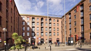 Un edificio de ladrillo de varios pisos con una entrada central, un asta de banderas y un cartel que dice 'Welcome to Albert Dock'.