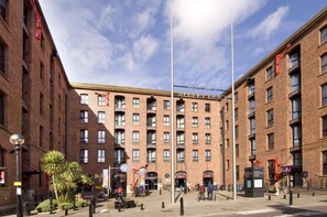 Un edificio de ladrillo de varios pisos con una entrada central, un asta de banderas y un cartel que dice 'Welcome to Albert Dock'.