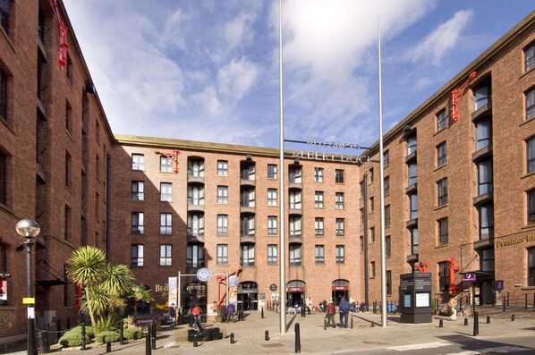 Un edificio de ladrillo de varios pisos con una entrada central, un asta de banderas y un cartel que dice 'Welcome to Albert Dock'.