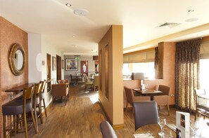 A hotel dining area with wooden tables and chairs, a bar area, and a reception desk. - Premier Inn Liverpool John Lennon Airport (Liverpool)