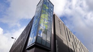 Un edificio moderno con una facciata in vetro che riflette il cielo e le nuvole.