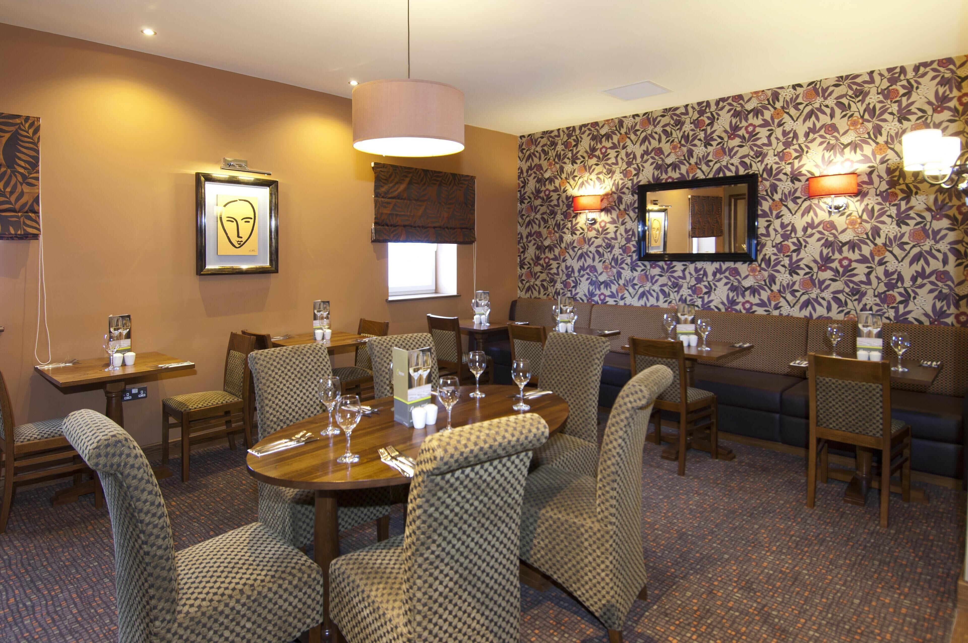 A hotel dining area with a round table, chairs, and a sofa.