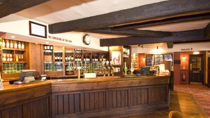 A bar area with wooden furnishings, a clock, and a sign indicating no smoking. - Premier Inn Tring (Tring)