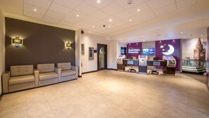 A hotel lobby with a reception desk, self-service kiosks, a chandelier, and a display case. - Premier Inn Manchester - Arena/Printworks (Manchester)