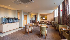 A hotel lobby with a coffee bar, seating area, and a large window with curtains. - Premier Inn Manchester - Arena/Printworks (Manchester)