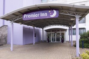 Ein Hotel Eingang mit überdachtem Gang, einem Schild für Premier Inn und einer Glastür.