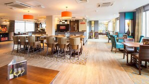A hotel lobby with a bar area, seating arrangements, and a reception desk. - Premier Inn Manchester - Arena/Printworks (Manchester)