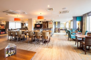 Um hall de hotel com área de bar, disposição de assentos e balcão de recepção.