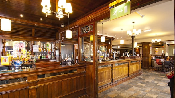 Eine Bar mit Holztresen, mehreren Lampen und einem gefliesten Boden.