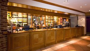 Eine Bar mit Holzwandverkleidung, einer Auswahl an Flaschen und einer Registrierkasse.
