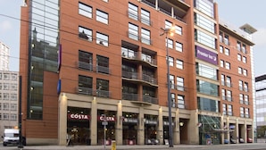 Ein mehrgeschossiges Hotel mit einem gut sichtbaren 'Premier Inn'-Schild, mehreren Balkonen und verschiedenen Gastronomiebetrieben im Erdgeschoss.