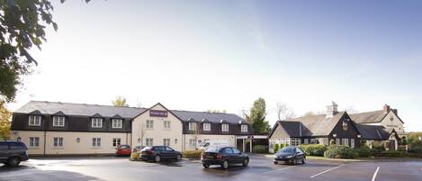 A hotel with a parking lot, a pub, and a building with a sign that reads 'Premier Inn.'