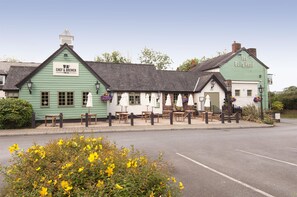 A pub with outdoor seating, a green exterior, and a sign reading 'The Bulls Head.' - Premier Inn Manchester - Handforth (Wilmslow)