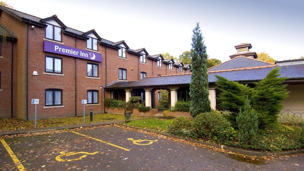 A brick building with a sign reading 'Premier Inn.' There is a parking area with a disabled parking symbol. - Premier Inn Manchester - Wilmslow (Wilmslow)