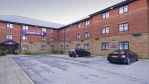 Een bakstenen gebouw met een bord voor 'Premier Inn' en twee auto's er voor geparkeerd.