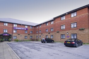 Ein Backsteinhaus mit einem Schild für 'Premier Inn' und zwei geparkten Autos davor.
