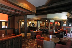 Un ambiente acogedor con vigas de madera, una zona de bar y diversas opciones de asientos.