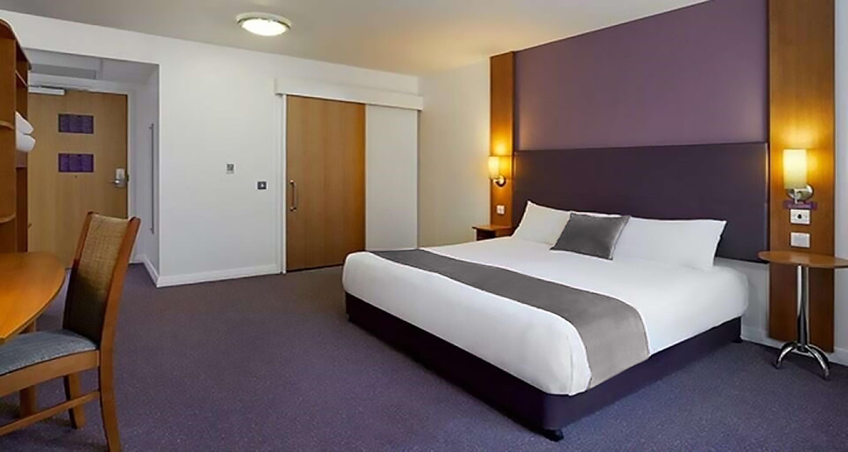 A hotel room with a large bed, a desk, and a chair.