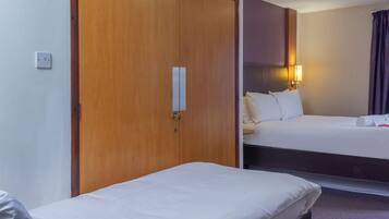 A hotel room with a wooden wardrobe, a single bed, and a smaller bed.