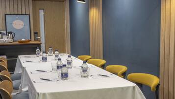 A conference room with a long table set for meetings, equipped with water bottles, pens, and notepads.