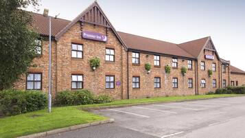 A brick building with 'Premier Inn' signage, multiple windows, and a parking lot.