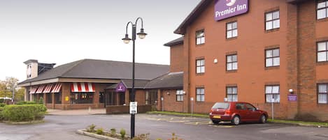 Ein Hotel mit Ziegelverkleidung, ein rotes Auto auf dem Parkplatz und ein Schild für Premier Inn.