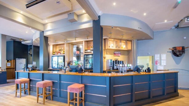 A bar area with stools, a counter, and a sign that reads 'COSTA.'