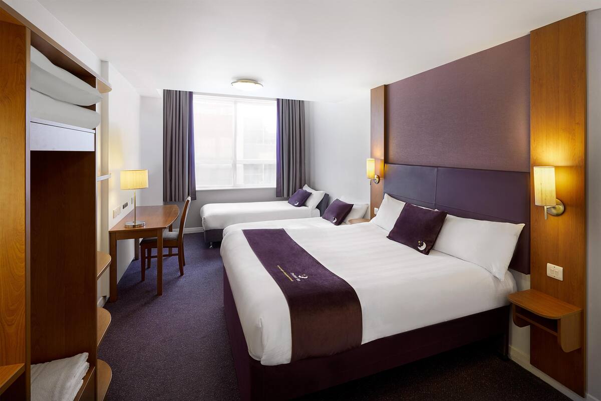 A hotel room with two beds, a desk, and a wardrobe.