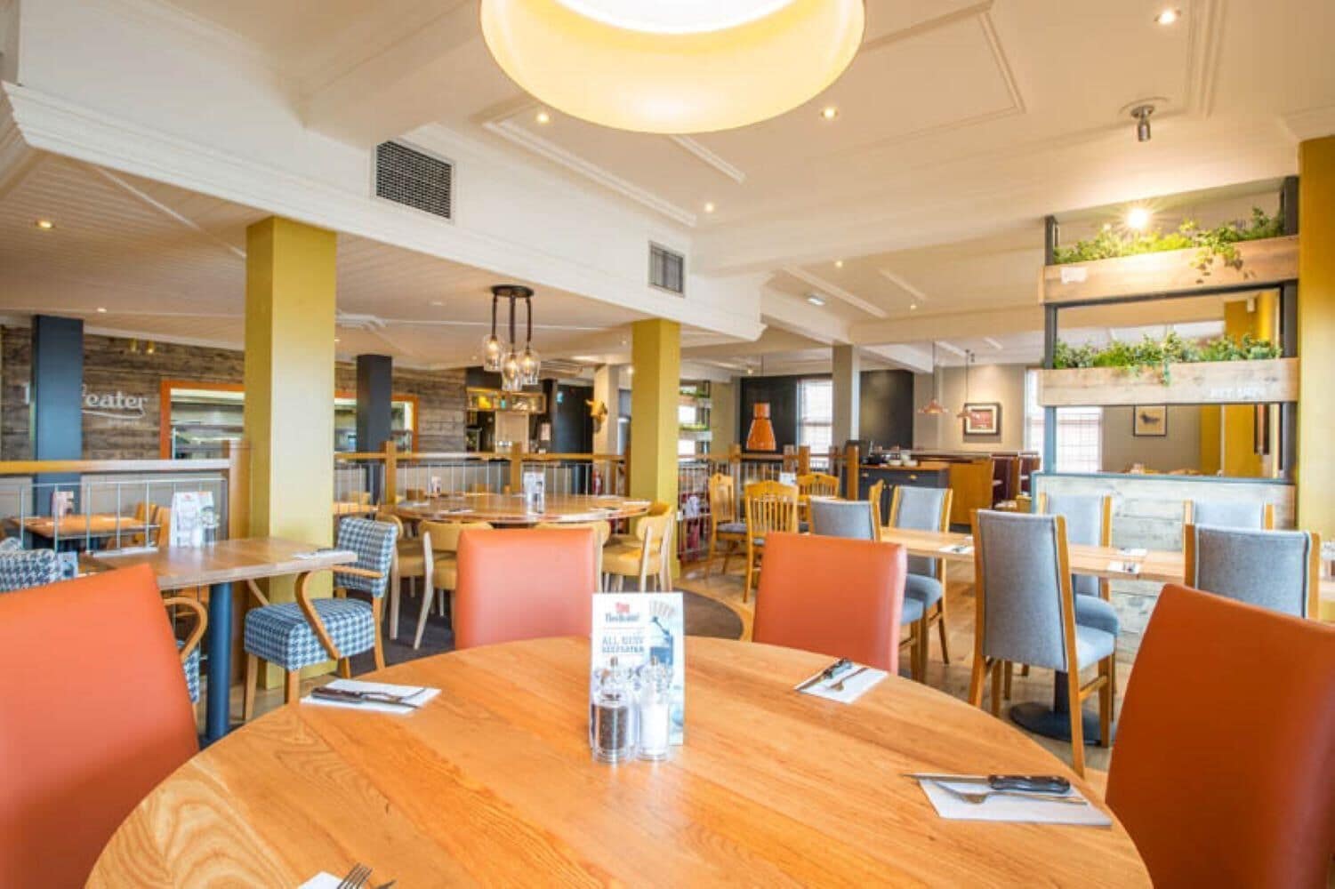 Ein Restaurant mit runden Tischen, Stühlen und einer zentralen Leuchte.