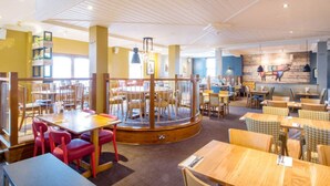 A restaurant with multiple dining areas, including a central round table surrounded by chairs and a separate dining section with individual tables and chairs.