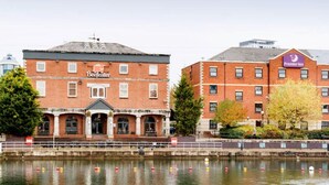 A historic building with a 'Beefeater' sign, a modern building with a 'Premier Inn' sign, and a canal in the foreground.